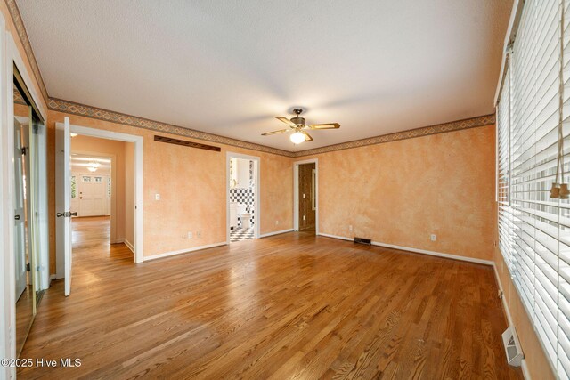 unfurnished room with ceiling fan, visible vents, baseboards, and light wood-style flooring