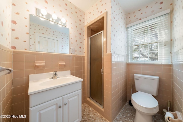 bathroom with vanity, a stall shower, wainscoting, and wallpapered walls