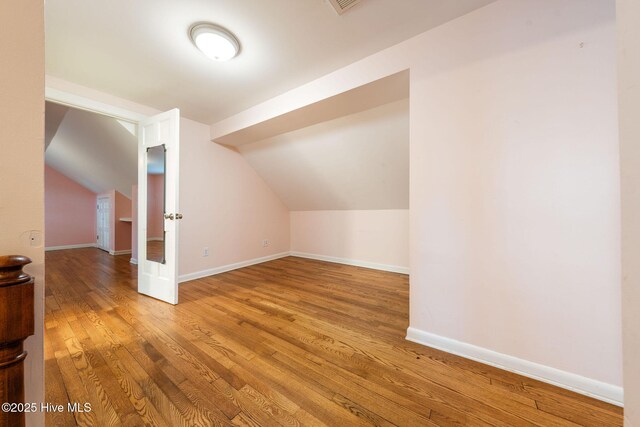 additional living space with vaulted ceiling, wood finished floors, and baseboards