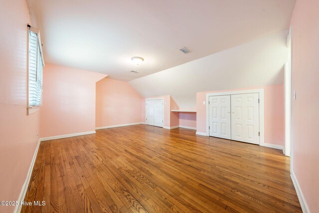 bonus room with baseboards, lofted ceiling, and wood finished floors