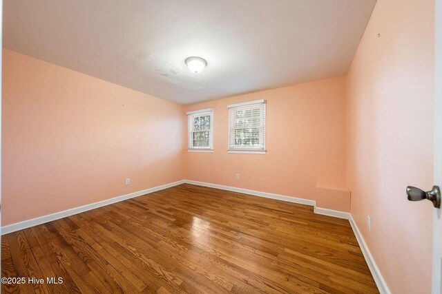 unfurnished room with baseboards and wood finished floors