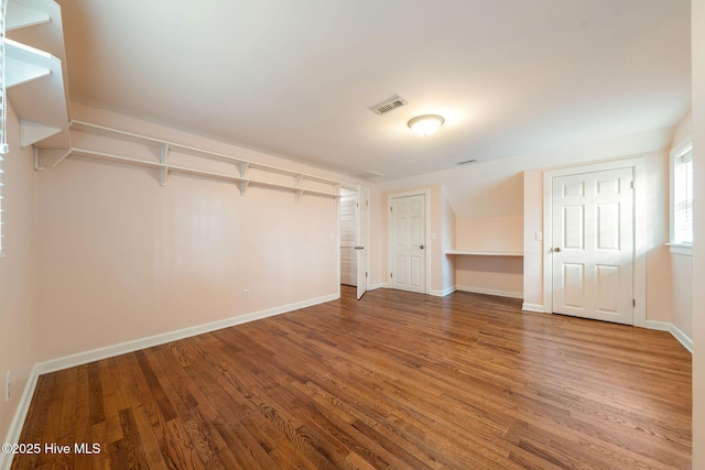 unfurnished bedroom featuring visible vents, wood finished floors, baseboards, and two closets