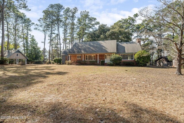 view of front of house with a front yard, brick siding, and a chimney