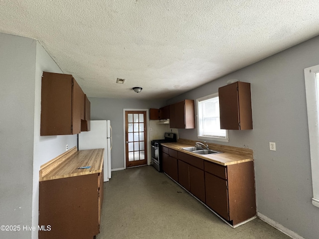 2604 Robeson St, Wilmington, NC 28405 - kitchen with stainless steel range with gas cooktop, freestanding refrigerator, light countertops, a sink, and a textured ceiling
