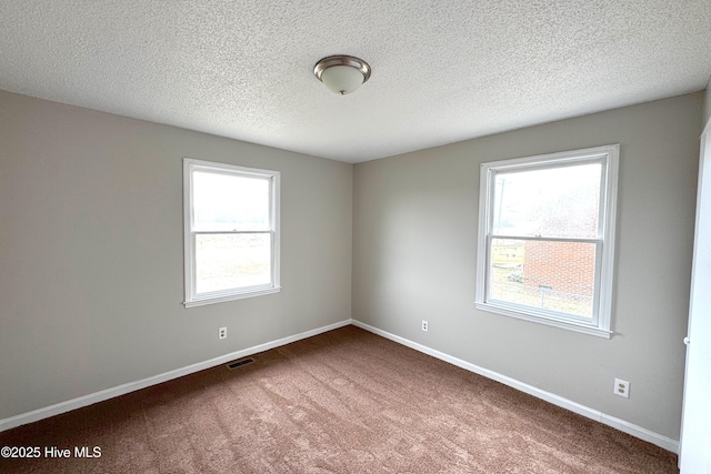 carpeted empty room featuring visible vents, baseboards, and a textured ceiling