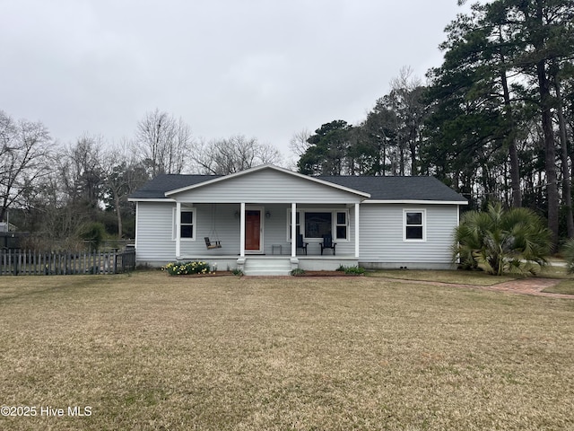 view of front facade featuring covered porch, a shingled roof, a front yard, and fence