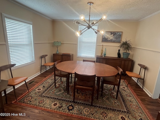 dining space featuring ornamental molding, wainscoting, an inviting chandelier, wood finished floors, and a textured ceiling