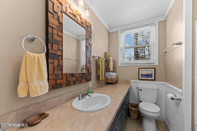 bathroom with vanity, wainscoting, crown molding, toilet, and tile patterned floors