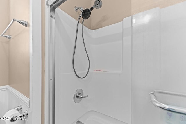 bathroom featuring a wainscoted wall and walk in shower