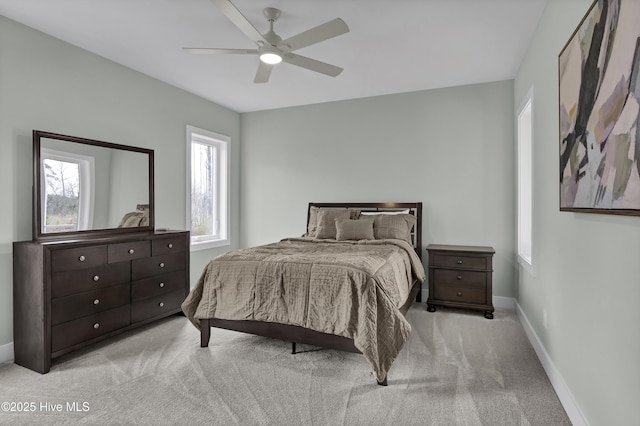 bedroom featuring light carpet, a ceiling fan, and baseboards