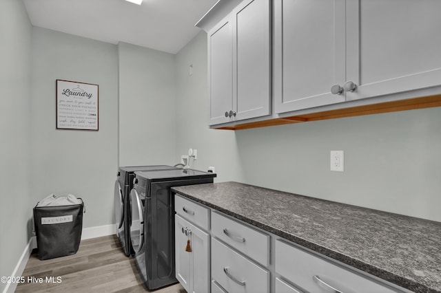 laundry area with light wood finished floors, baseboards, cabinet space, and washer and clothes dryer