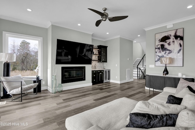 living room with ceiling fan, stairway, beverage cooler, and crown molding