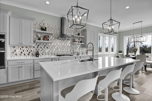 kitchen featuring a notable chandelier, a sink, wall chimney exhaust hood, and open shelves