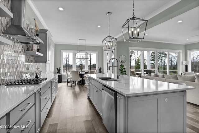 kitchen with a sink, appliances with stainless steel finishes, wall chimney exhaust hood, and ornamental molding