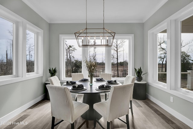 dining area with light wood-style flooring, baseboards, a chandelier, and crown molding