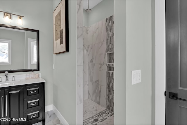 bathroom featuring baseboards, marble finish floor, vanity, and a walk in shower