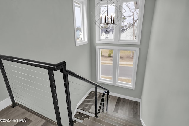 staircase with baseboards, an inviting chandelier, and wood finished floors