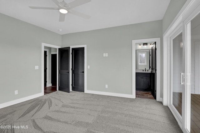 carpeted bedroom featuring ceiling fan, ensuite bathroom, baseboards, and a sink