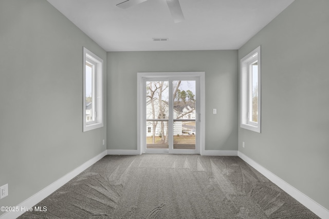 carpeted spare room featuring baseboards, visible vents, and ceiling fan