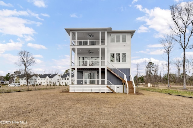 back of property featuring a lawn, a ceiling fan, board and batten siding, a sunroom, and stairs