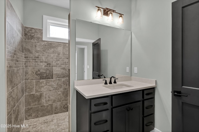 full bathroom featuring a tile shower and vanity