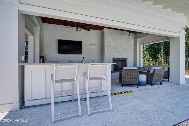 view of patio featuring exterior bar, outdoor lounge area, and a ceiling fan