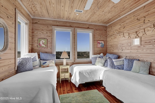 bedroom with multiple windows, wood ceiling, wood finished floors, and wood walls