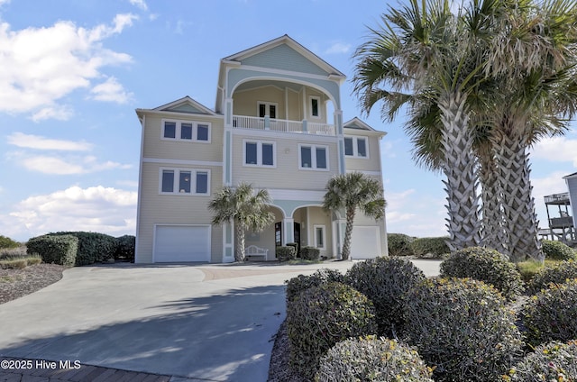 coastal home featuring a garage, a balcony, and concrete driveway