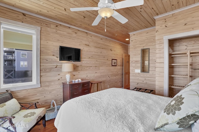 bedroom with wooden walls, wood ceiling, a ceiling fan, and wood finished floors