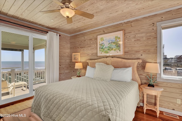 bedroom featuring visible vents, a water view, wood finished floors, wooden ceiling, and access to exterior