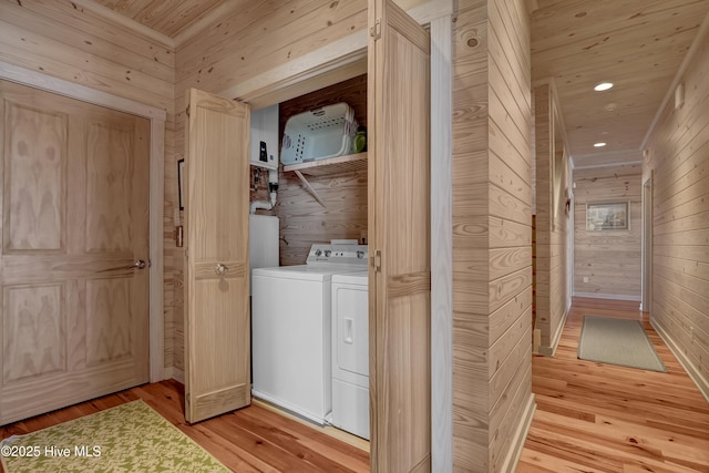 laundry room with light wood-style floors, wood walls, laundry area, and washer and clothes dryer