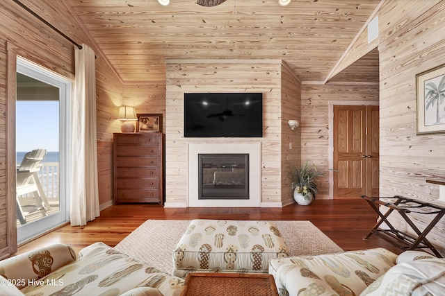 living area with a glass covered fireplace, wood finished floors, wooden ceiling, and vaulted ceiling