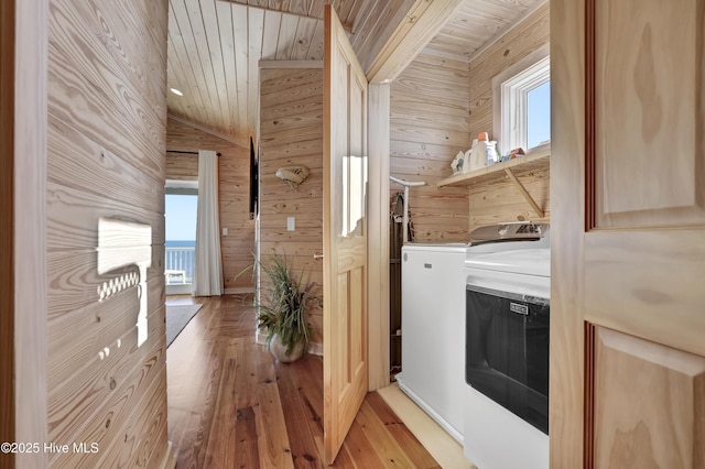 clothes washing area with wood ceiling, wood walls, laundry area, and washing machine and clothes dryer