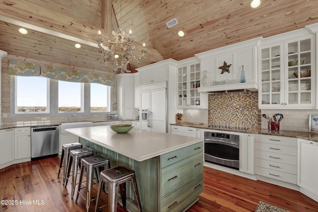 kitchen with a center island, wood ceiling, appliances with stainless steel finishes, a kitchen breakfast bar, and white cabinetry