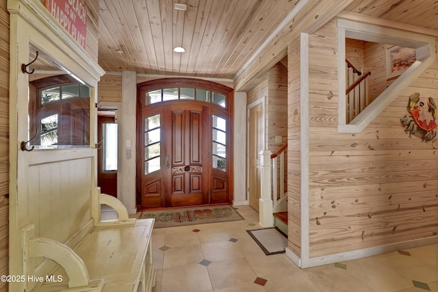 entrance foyer featuring stairs, wooden ceiling, a healthy amount of sunlight, and wood walls