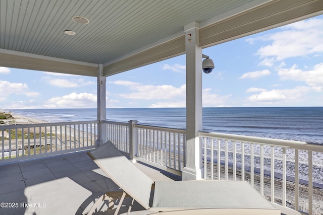 view of patio featuring a view of the beach, a balcony, and a water view