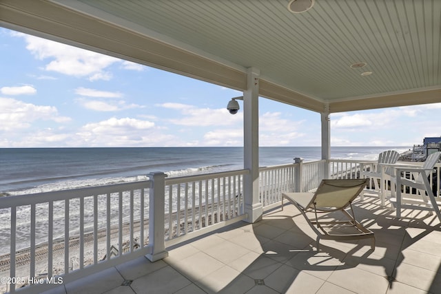 view of patio with a water view and a beach view