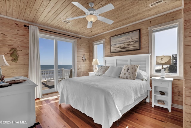 bedroom with wooden walls, wood finished floors, visible vents, wood ceiling, and access to outside