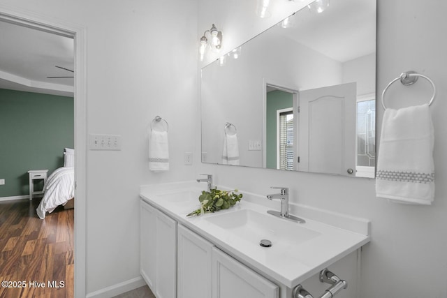 ensuite bathroom with a sink, ensuite bath, wood finished floors, and double vanity