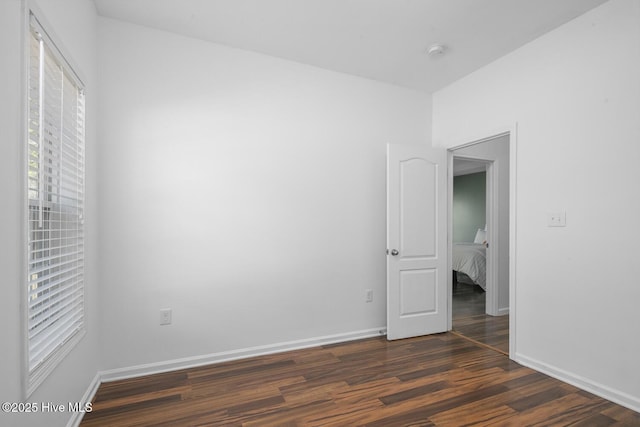 unfurnished bedroom featuring baseboards and dark wood-type flooring