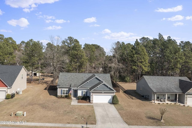 ranch-style home featuring a front yard, concrete driveway, a garage, and a shingled roof