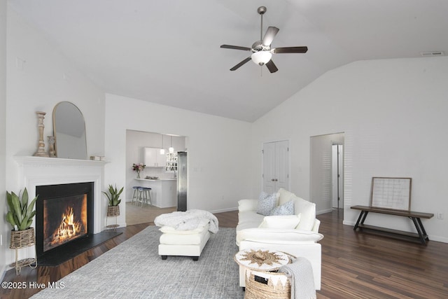 living area featuring visible vents, a ceiling fan, a lit fireplace, and wood finished floors