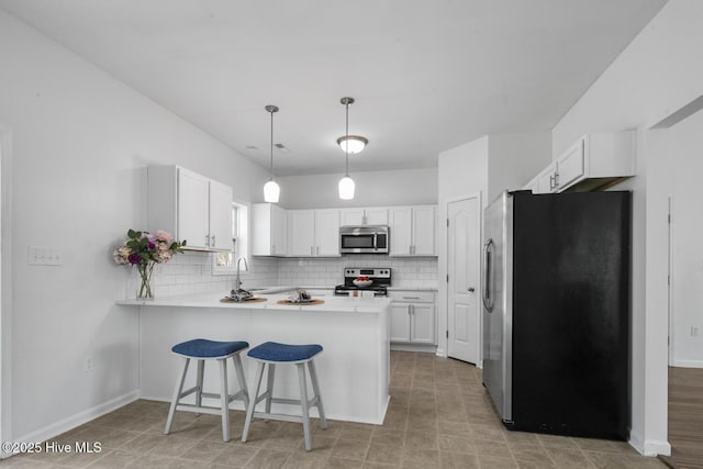 kitchen featuring backsplash, a peninsula, stainless steel appliances, and light countertops