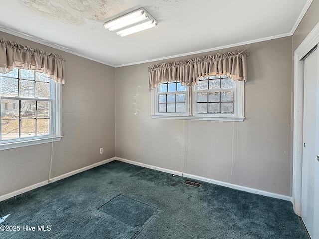 spare room with a wealth of natural light, ornamental molding, and dark carpet