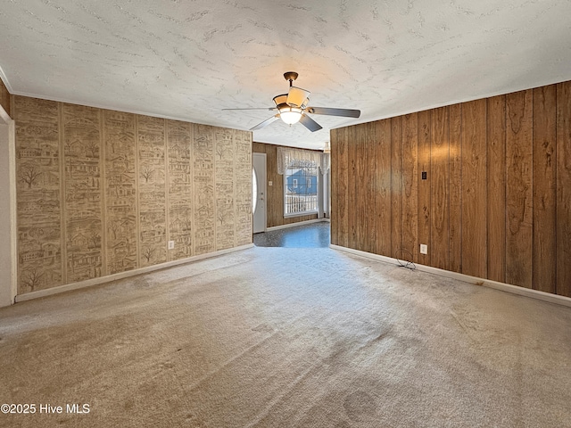 unfurnished room with wooden walls, carpet flooring, and ceiling fan