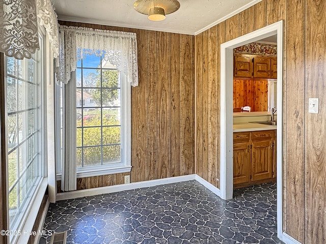 empty room featuring a wealth of natural light, wooden walls, visible vents, and ornamental molding