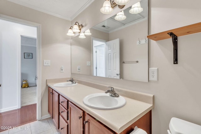 bathroom featuring double vanity, toilet, crown molding, and a sink