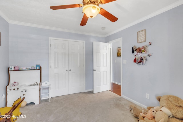 bedroom with crown molding, ceiling fan, baseboards, carpet floors, and a closet