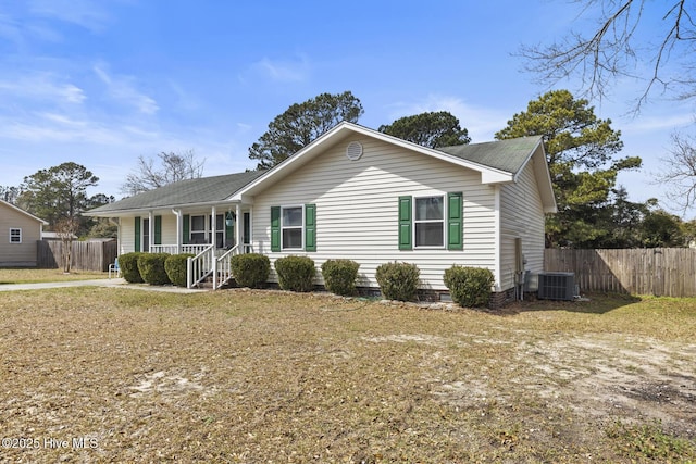 ranch-style house featuring central air condition unit, covered porch, and fence