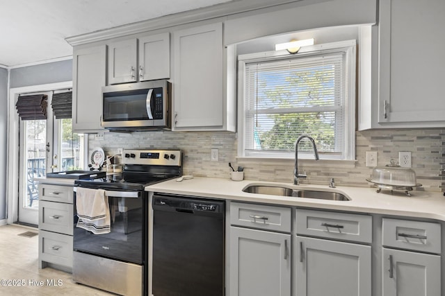 kitchen featuring decorative backsplash, light countertops, appliances with stainless steel finishes, and a sink